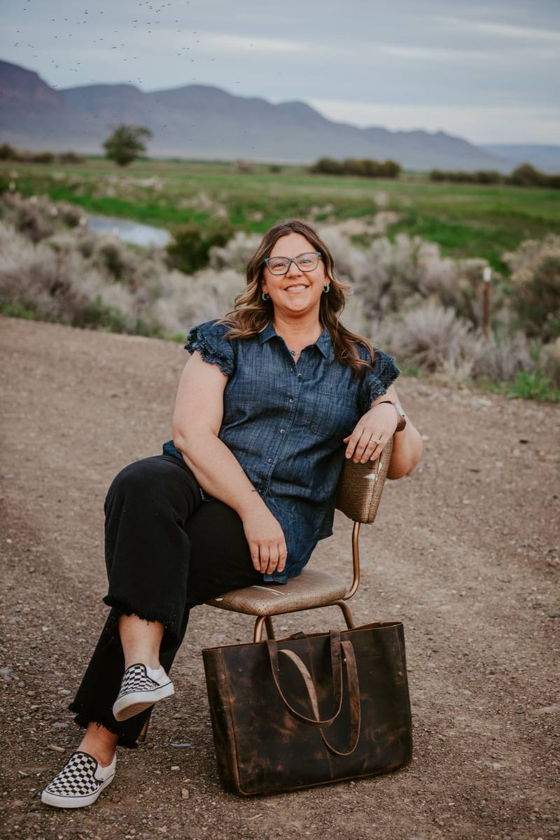 Rachel Cooper sitting on a chair on a dirt road with mountains in the background